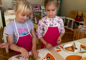 dziewczynki stoją przed talerzami z pizzą