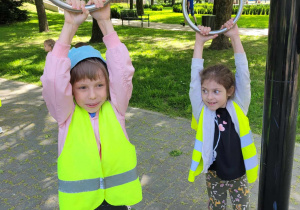 dwoje dzieci ćwiczy na sprzęcie gimnastycznym podciagając się rękoma na kołach