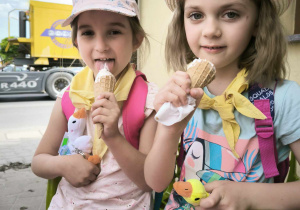 dwie dziewczynki siedzą i jedzą lody