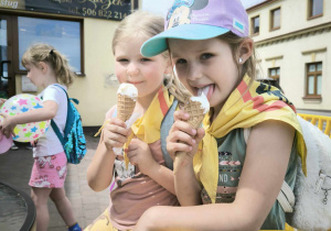 dwie dziewczynki siedzą na krzesłach i jedzą lody