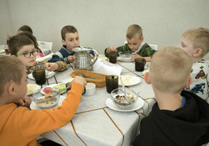 chłopcy siedzą za stolem i jedż płatki na mleku