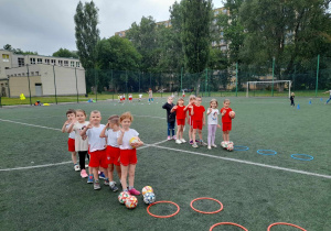 dzieci stoją z piłkami w rękach i czekają na start konkurencji