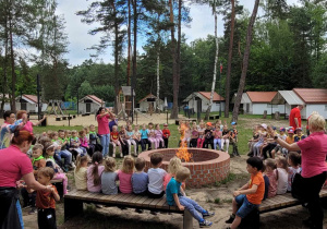 wszystkie grupy siedzą przy ognisku i spiewają piosenkę