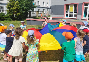 Uśmiechnięte dzieci poruszają się po kole z chustą animacyjną.