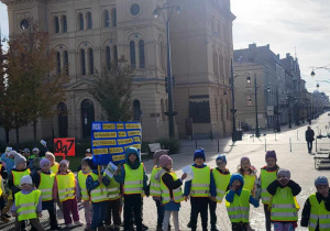 Dzieci stoja na tle kościoła na Placu Wolności