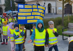 dzieci idą w parach niosąc tablicę z informacją o projekcie L 047