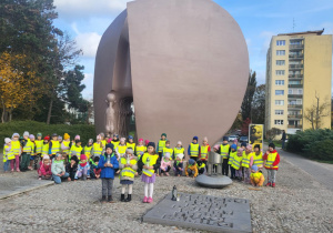 Dzieci stoją pod pomnikiem ze zniczami