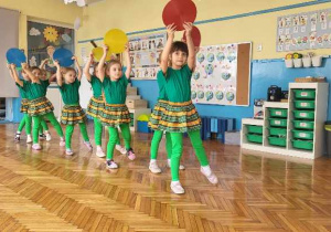 dziewczyny z grupy trzeciej w zielonych strojach do tańca, prezentują układd tanczny z wykorzystanim krążków