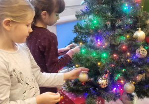 Dziewczynki zawieszają złote ozdoby choinkowe