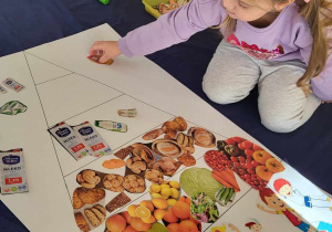 dziewczynka wybiera obrazki i dopasowuje produkty do wybranego piętra piramidy żywieniowej