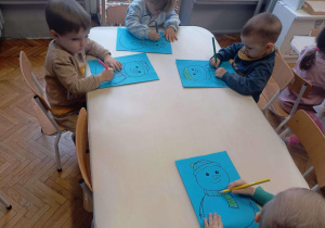 Dzieci przy stoliku kolorują szaliki bałwankom