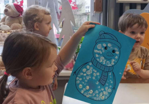 Dziewczynka pokazuje zimowego bałwanka