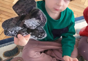 chłopiec pokazuje trzymany w ręku węgiel