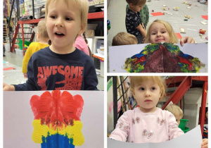 dzieci prezentują swoje prace, na których są namalowane symetryczne kolorowe plamy