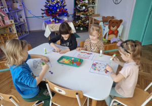 Dzieci przyklejają kolorowe kartoniki na sukience babci