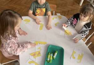 Dzieci przy stoliku układają obrazek z części