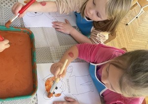Dziewczynki na brązowo malują farbami Misia Uszatka