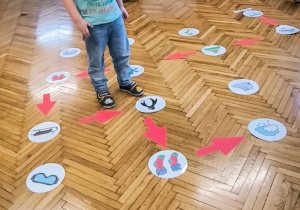 Chłopiec stoi przed kasrtą do kodowania, na której jest narysowany pingwin
