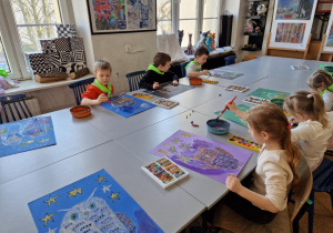widać salę plastyczną z dziećmi przy stolikach malującymi