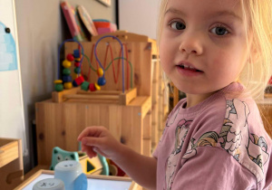 Dziewczynka układa kubeczki z koloroami zielonym i niebieskim
