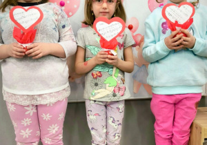 trzy dziewczynki pozują do zdjęcia z walentynkami własnej roboty