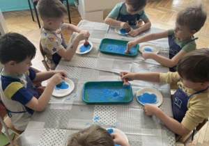 Dzieci malują na niebiesko talerze papierowe