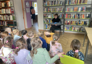 Dzieci słuchają czytanej przez panią bibliotekarkę bajki