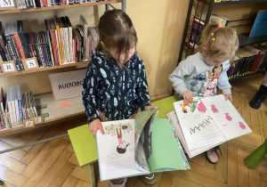 Dziewczynki siedza naławce i oglądają książeczki