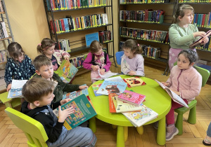 Dziei siedzą w bibliotece i oglądają książeczki