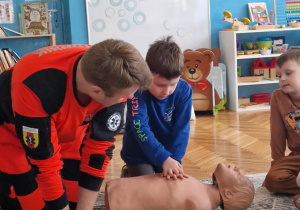 Chłopiec uciska klatkę piersiową fantoma
