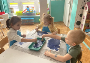 Dzieci malują niebieską farbą karton
