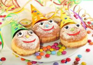 trzy pączki na talerzu z buźkami