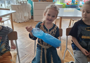 Dziewczynka miesza wodę w butelce z niebieską farbą