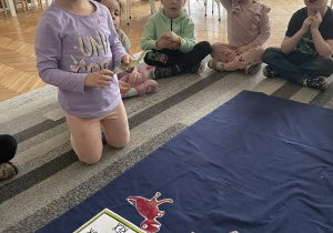 Dziewczynka zastanawia się gdzie połozyć papierowego dinozaura