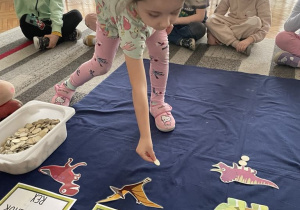 Dziewczynka uklada tyle żetonów ile jest Pterodaktyli