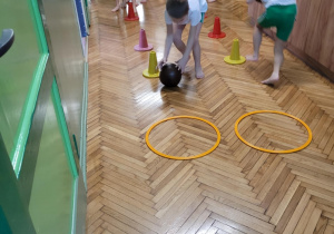 Chłopiec z dziewczynkąturlają piłkę po slalomie