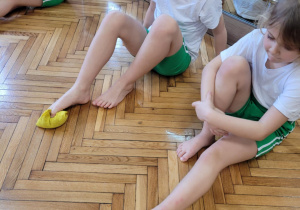 Dzieci palcami u stóp podnoszą woreczki