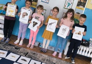 Dzieci pokazują ilustracje zwierząt zyjących na kontynencie afrykańskim