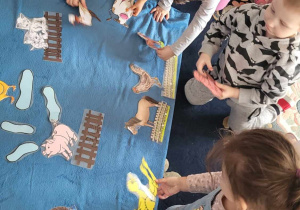 dzieci tworzą makietę wiejskiej zagody ukladając ziwerzęta - kozy, świnie, krowy