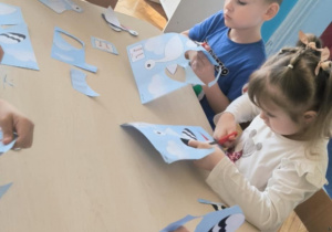 Dzieci przy stoliku wycinają po śladzie