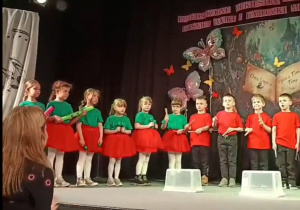 Dzieci stoją na scenie z instrumentamiw dłoniach