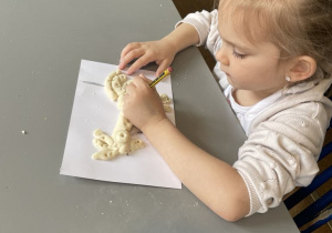 Dziewczynka ołówiekm robi wzorki w masie solnej