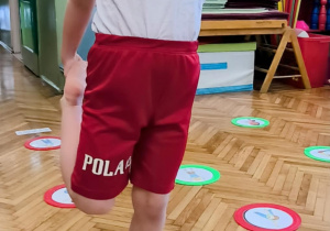Chłopie stoi na jednej nodze z wyciągnięta do przodu ręką