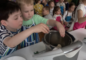 Chłopcy wrzucają pokrojony chrzan do misy robota