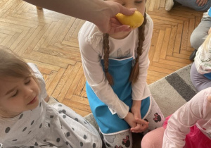 Dziewczynka wącha cytrynę z zamkniętymi oczami