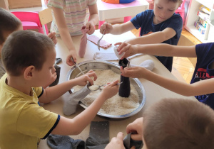 Dzieci nabierają ryż i wsypuja do skarpet