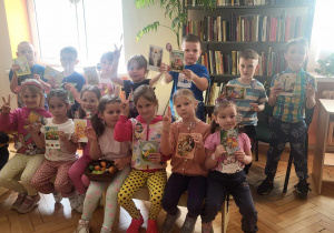 dzieci pozują do zdjęcia z pocztówkami