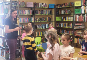 dzieci i pani bibliotekarka poszukują pisanki pomiędzy książkami