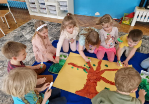 dzieci w czasie wspólnej racy plastycznej układając drzewo z bibuły