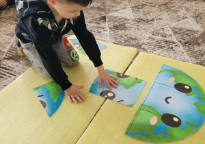 Chlopiec układa puzzle z Ziemią smutną i wesołą